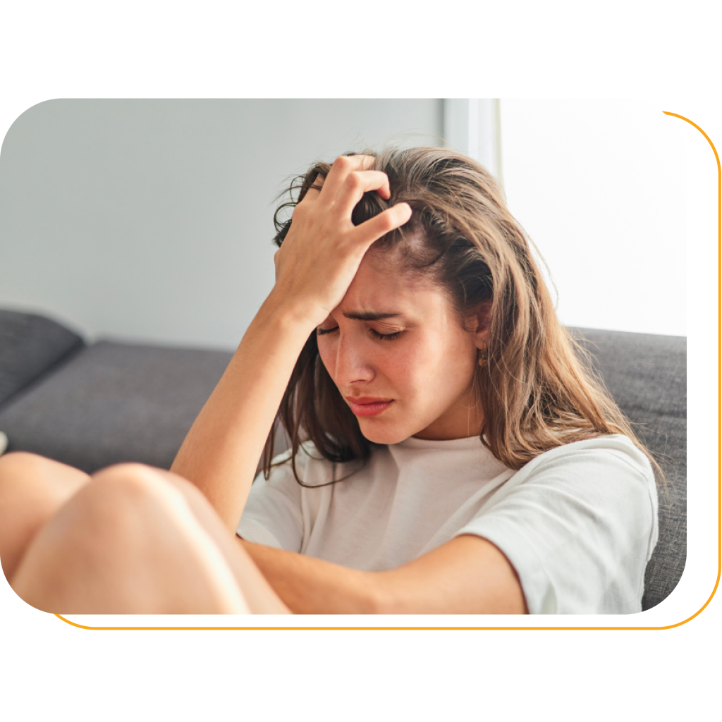 A teenager is having depression by grabbing her hair and showing a distressed expression