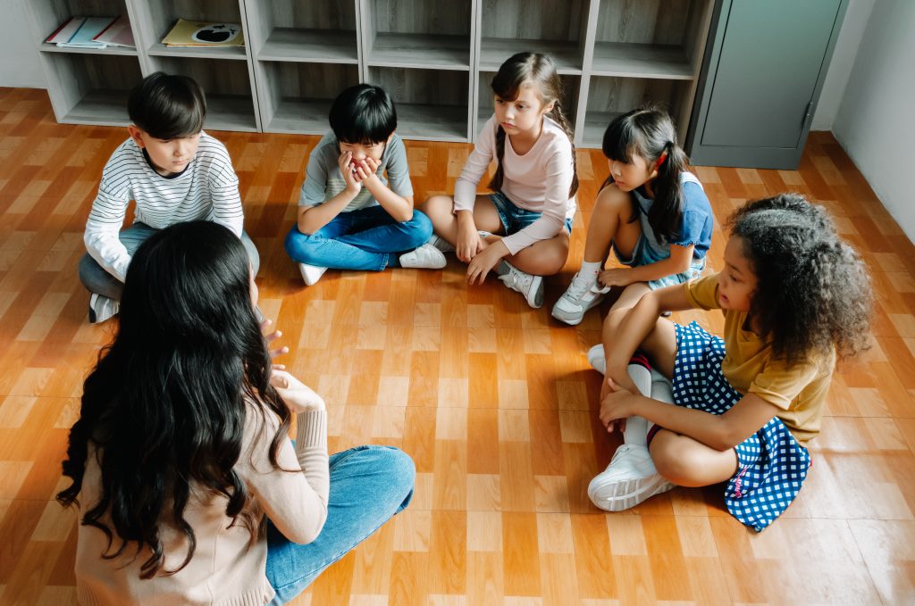 Elementary international students group sit cross legged in circ